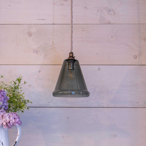 Rye Small Smoked Glass conical pendant light hanging with exposed bulb and wooden wall background