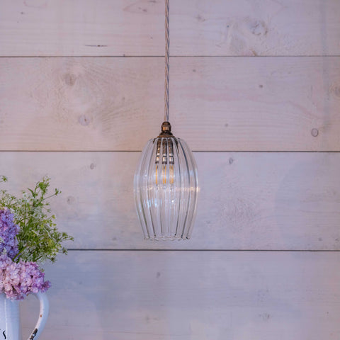 Camber Small Ribbed Glass Shade pendant light hanging in room with wooden wall background