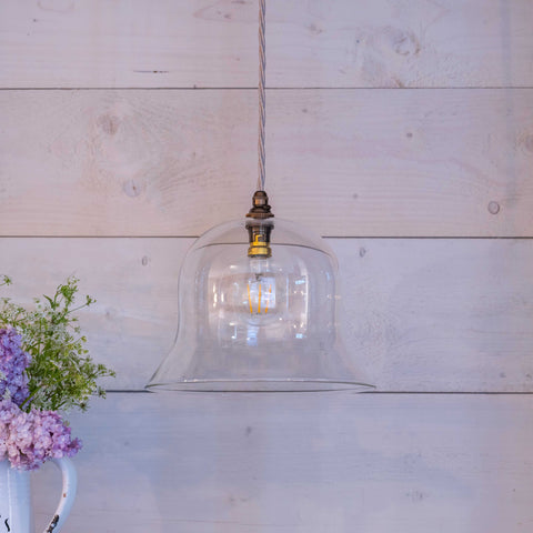 Bodium Large clear glass pendant light with adjustable flex and modern design hanging against wooden wall