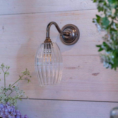 Camber small ribbed glass shade wall light with fluted hand blown glass and brushed metal arm mounted on white wooden wall