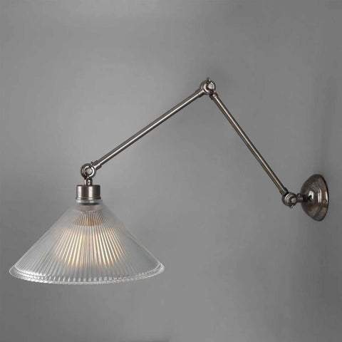Rebell Prismatic Adjustable Wall Light with prismatic glass shade and adjustable brass arm mounted on gray wall