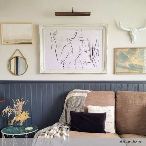 Dublin Picture Light solid brass adjustable wall light illuminating artwork above sofa in cozy living room