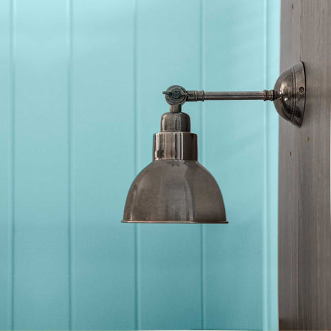 Moorlea Brass Wall Light vintage adjustable metal wall sconce with industrial aged finish against blue paneled wall