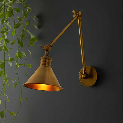 Pooky Stork Wall Light brass adjustable arm vintage style mounted on dark wall with warm glow