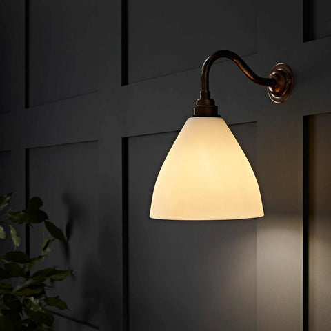 Langton Ceramic Shade Wall Light with matte ceramic shade and warm glow mounted on dark paneled wall
