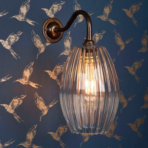 Camber Medium Ribbed Glass wall light with fluted glass shade and bronze finish mounted on blue patterned wall