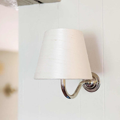 Finberry Cream Silk wall light with cream silk shade and curved polished brass arm mounted on white wall
