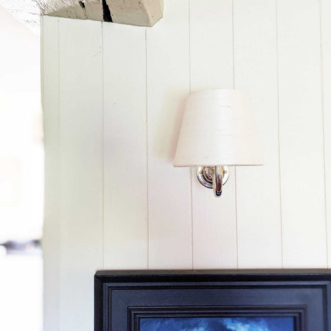 Finberry Cream Silk fabric shade wall light with curved brass swan neck mounted on white wooden wall above framed artwork