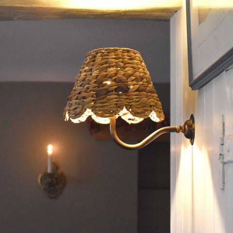 Natural seagrass shade wall light with antique brass fitting creating warm ambient lighting