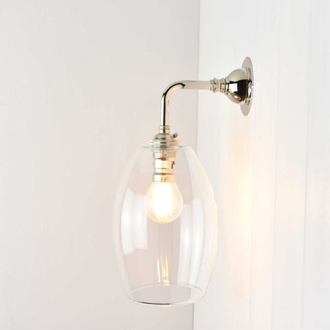 Camber Small Clear Glass Shade wall light with elongated clear glass shade and polished metal arm, modern and elegant wall-mounted lighting fixture.