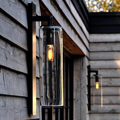 Contemporary dome outdoor wall light with black metal frame and unique mouth-blown glass, mounted on wooden exterior wall, suitable for porch or garden lighting.