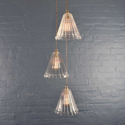 Rye medium ribbed glass shade cluster pendant light with three hand-blown glass shades hanging against a gray brick wall