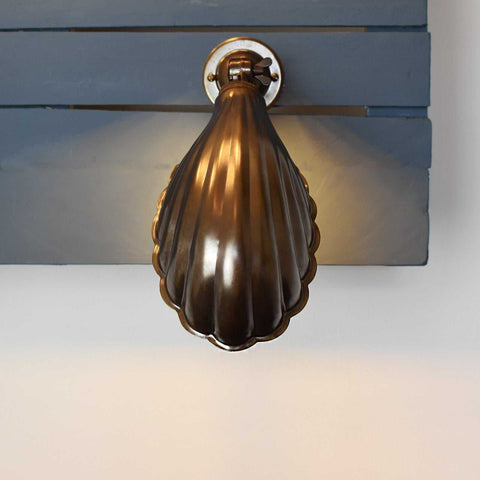 Hadlow Adjustable Brass Shell Wall Light in antique brass finish with vintage shell design mounted on wall providing warm, adjustable illumination