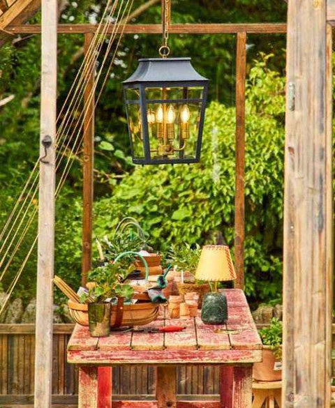Modern garden with layered outdoor lighting including wall and pendant lights at dusk in spring 2026