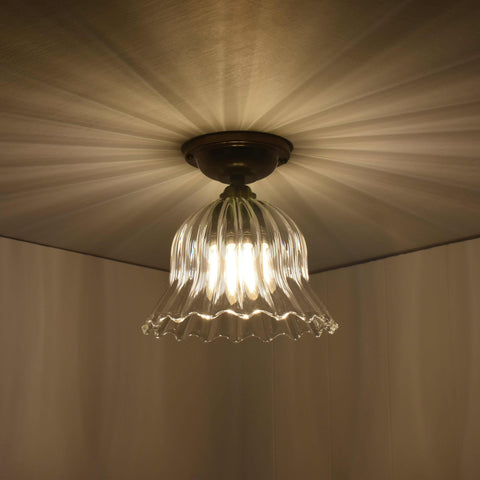 Bodium small ribbed glass shade flush ceiling light with flower-inspired design casting ambient light patterns.