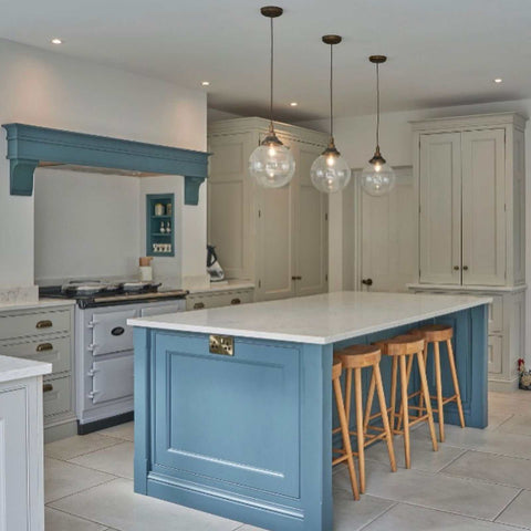Modern kitchen with three Laguna Bathroom Pendant lights featuring elegant glass globe shades hanging above a blue island with wooden stools