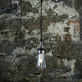 Bo Bathroom Pendant Light with clear teardrop glass shade and black fixture against rustic stone wall background, water-resistant for bathroom and outdoor use