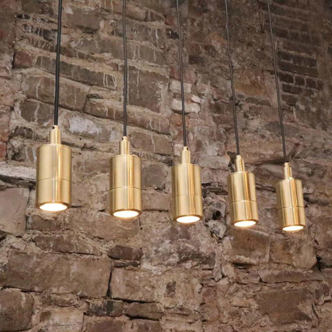 Ennis IP44 Spot Pendant Light set with sleek cylindrical brass fixtures hanging against a rustic brick wall