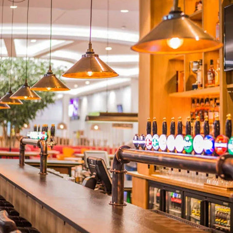 Hadleigh bathroom pendant light with industrial brass shade hanging above bar counter in modern indoor setting
