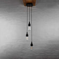 Bo Bathroom Cluster pendant light with three hanging bulbs and black fixtures against a gray brick wall