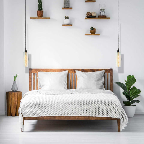 Bramley Bathroom clear long glass pendant lights hanging on either side of a wooden bed in a minimalist bedroom