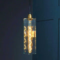 Bramley Bathroom clear long glass pendant light with decorative LED bulb hanging against dark wall