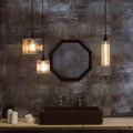 Bramley Bathroom reed glass long pendant lights with warm filament bulbs over dark sink and rustic wall