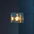 Bramley Bathroom clear glass cube pendant light with exposed filament bulb hanging against dark blue wall