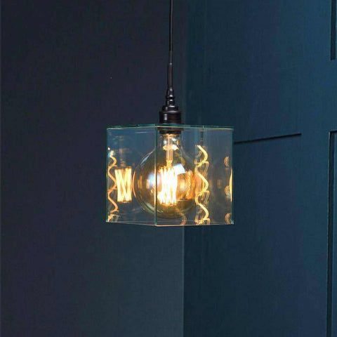 Bramley Bathroom clear glass cube pendant light with exposed filament bulb hanging against dark blue wall