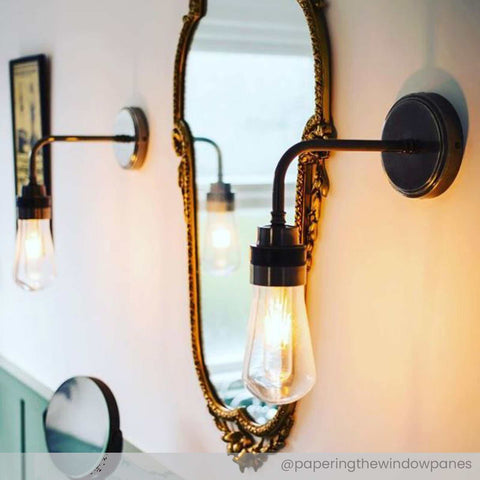 Bo Bathroom Wall industrial-style dimmable wall light with clear teardrop glass shade and black metal finish mounted beside ornate mirror