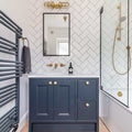 Modern bathroom interior featuring Clayton Bathroom Double Well Wall Light above a mirror, blue vanity, and gold fixtures