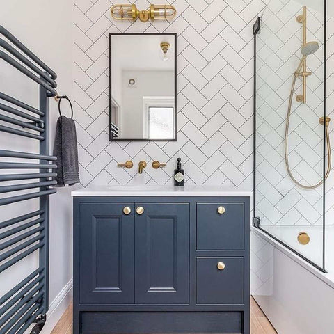 Modern bathroom interior featuring Clayton Bathroom Double Well Wall Light above a mirror, blue vanity, and gold fixtures