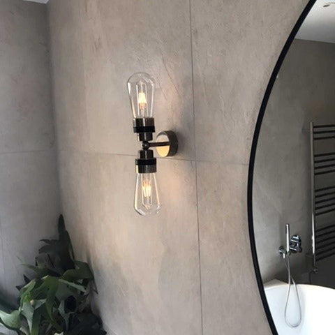 Aldbury Bathroom double wall light with two clear glass shades in matte black finish mounted on bathroom wall near round mirror