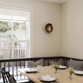 Chulainn Bathroom Dish Wall Light with antique brass finish mounted on wall in modern dining area with natural light