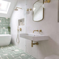 Modern bathroom with white tiles, gold fixtures, and a patterned green floor.