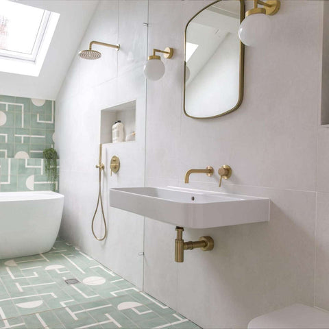 Modern bathroom with white tiles, gold fixtures, and a patterned green floor.