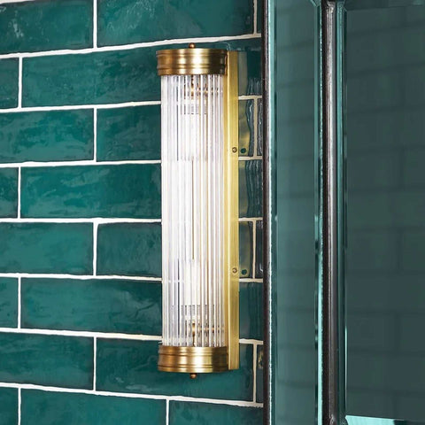Pooky Long Roddy bathroom wall light with brass frame and vertical glass rods mounted on green tiled wall