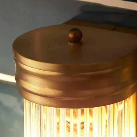 Close-up of Pooky Long Roddy bathroom wall light with gold finish and illuminated glass rods