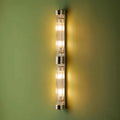 Pooky Rodtastic Bathroom Wall Light modern vertical design with warm illumination and sleek metallic finish on green wall