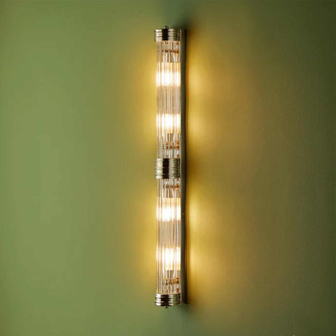 Pooky Rodtastic Bathroom Wall Light modern vertical design with warm illumination and sleek metallic finish on green wall