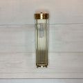 Decorative wall sconce with bright brass finish on a light wooden panel background