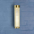Brass cylindrical wall light fixture on a blue textured wall