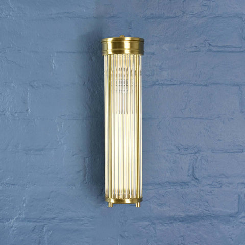 Brass cylindrical wall light fixture on a blue textured wall