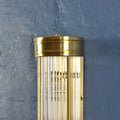 Brass wall-mounted light fixture against a blue wall