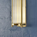 Gold cylindrical wall light fixture on a textured blue wall