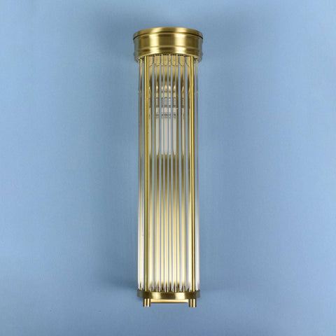 Decorative cylindrical light fixture with gold finish on a blue background
