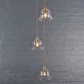 Bodium Small Clear Glass Shade cluster pendant light with hand-blown glass shades and adjustable cords against a gray brick wall background