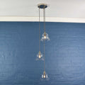 Bodium small clear glass shade cluster pendant light with adjustable flex and hand-finished metalwork against blue wall