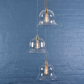 Bodium large clear glass shade cluster pendant light with hand-blown shades and adjustable cords against blue brick wall