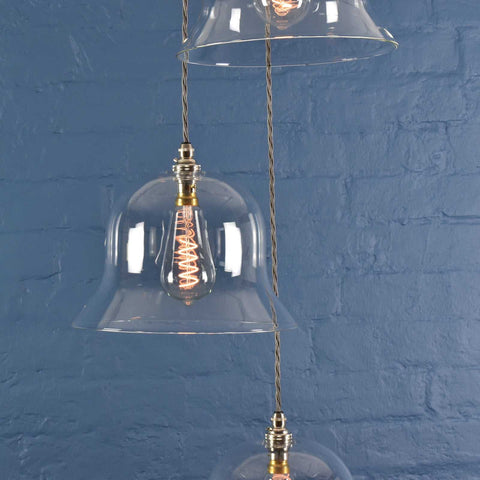 Bodium large clear glass shade cluster pendant light with hand-blown glass shades and vintage filament bulbs against blue brick wall